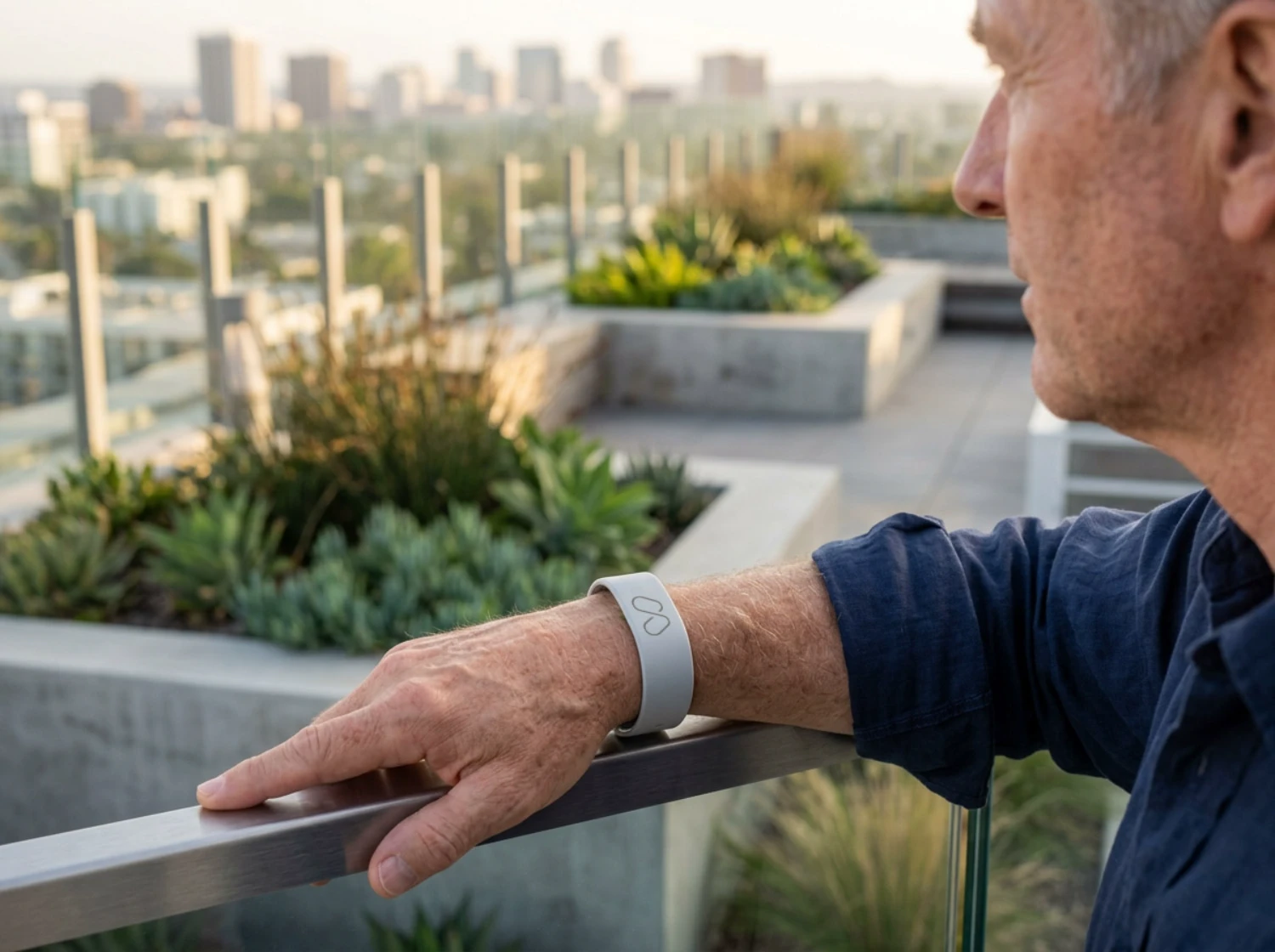 Wizmi-wrist-of-a-60yearold-man-wearing-a-wizmiband1-slim-light-grey-wizmi-health-monitoring-wristband-his-hand-resting-relaxed-on-a-railin_0001-2